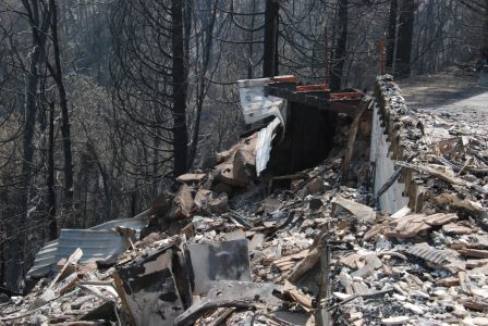 Image of rubble and burned metal frameworks piled below foundation walls