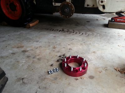 Image of a red aluminum wheel spacer next to the Bobcat