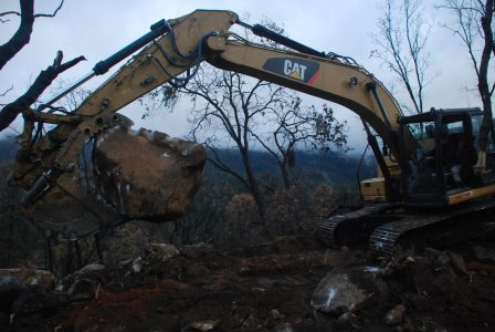 Image of a large boulder in the jaws of the excavator