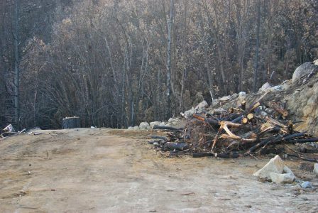 Image of a large pile of brush and wood on the otherwise empty space where the Logger's Retreat garage used to be