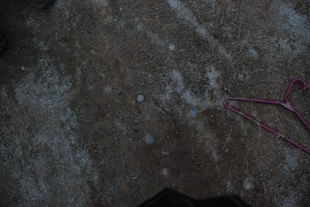 Image of a pink coathanger lying in the dirt