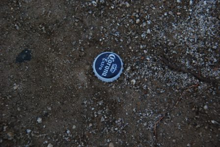 Image of a Corona Extra bottle cap in the dirt