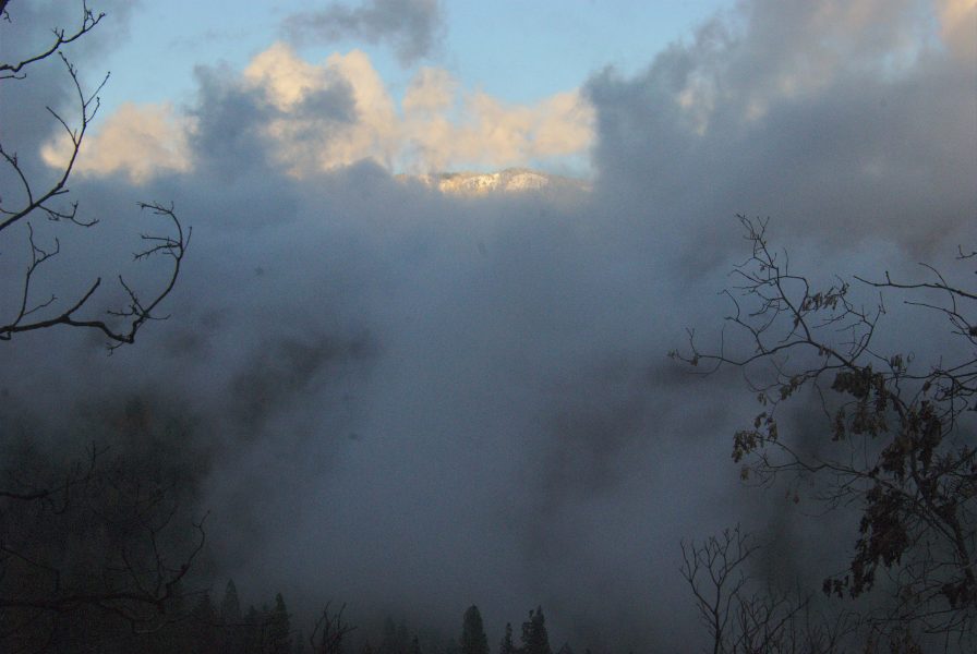 Image of nearby clouds with a snow-capped mountain and blue sky in the background