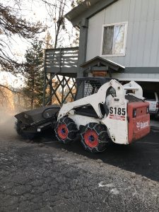 Image of Bobcat with brush attachment clearing snow in front of the house