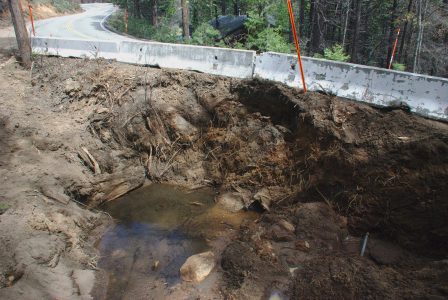 Image of a deep pit beside the highway, mostly empty of water now