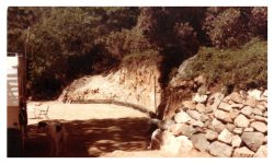 Image of flat graded area and dirt wall, rocks and a line of railroad ties