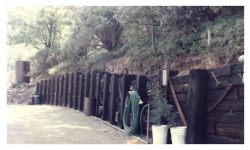 Image of completed railroad-tie retaining wall with old rusty tools hung on it